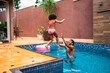 © Nexa - Happy father catching his young daughter as she jumps into a backyard swimming pool during a sunny summer day.