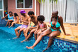 © Nexa - Diverse group of happy friends and family relaxing by the swimming pool with drinks during a summer vacation.