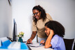 © Nexa - African American mother helping her teenage daughter with school homework at a desk in a home office.