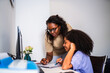 © Nexa - African American mother or tutor helping a teenage girl with her studies at a desk in a home office.