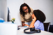 © Nexa - African American mother helping her daughter with schoolwork at a desk in a home office.
