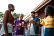 © Nexa - Happy multi-generational diverse friends and family celebrating together with a beer toast at a backyard barbecue party on a sunny day.