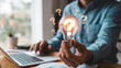 © MD SHADIKUL ISLAM - A person holding a glowing light bulb with question marks around it