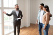© Prostock-studio - Professional Male Reator In Suit Showing New Apartment To Young Arab Couple, Looking And Pointing At Beautiful View From Big Floor To Ceiling Windows. Happy Guy And Lady Talking With Seller
