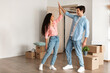 © Prostock-studio - Young couple shares a joyful high five in their new house, celebrating moving day with excitement. Surrounded by boxes, they embrace their fresh start as proud first-time homeowners.