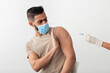 © Prostock-studio - Young Arab guy in face mask stopping doctor from making covid vaccine injection, being against coronavirus immunization on white studio background. Eastern man refusing corona vaccination