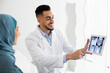 © Prostock-studio - Handsome Arab Dentist Doctor Showing Teeth Xray Shot On Digital Tablet To Muslim Female Patient In Hijab, Demonstrating Dental Treatment Result During Check Up In Modern Stomatological Clinic