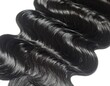 © Printer - Close-up of glossy, dark, wavy locks. Soft light highlights the smooth strands and natural curvature. A rich, dark beauty