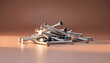 © DrewDuzz - A pile of shiny metal nails is scattered on a smooth surface under warm lighting with a soft brown background creating a simple and clean industrial appearance