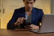 © AK ST - Man Using Smartphone While Working on Laptop at Wooden Desk