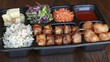 © diajengwd - Asian-style meal served in a black plastic compartmentalized container.