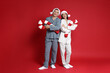 © New Africa - Happy couple in Santa hats and decorative candy canes on red background. Christmas atmosphere