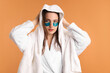 © New Africa - Beautiful woman wearing eye patches drying hair with towel on orange background