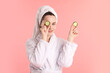 © New Africa - Woman wearing bathrobe with hair wrapped in towel holding cucumber slices on pink background