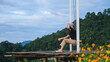 © Farknot Architect - Portrait image of a woman sitting on a swing with a beautiful flower garden and mountain on cloudy day