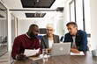 © Jelena - Business Meeting With Colleagues Reviewing Documents And Laptop In Modern Office