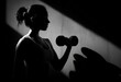 © oksa_studio - Young woman working out with a dumbbell, emphasizing strength, fitness, and determination in a high contrast black and white scene with copy space