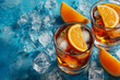 © alenagurenchuk - Two glasses of refreshing non alcoholic drinks, garnished with orange slices and ice cubes on a blue background