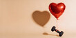 © Giggles - Heart balloon lifting dumbbell on warm background with copy space, fitness motivation and self love strength concept