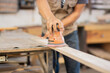 © YanlethRivera - Close-up of a man using a hand sander. Carpenter sanding wood on a workbench