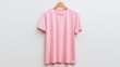 © Tanvir - A simple pink t-shirt is displayed on a wooden hanger against a white background, showcasing its casual style and versatile look.