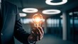 © Bayu Tri Nugroho - Business professional holding glowing light bulb symbolizing innovation creativity ideas and problem solving in modern office environment for corporate success