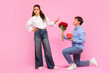 © Home-stock - Guy standing on one knee with flowers and gift for Valentine's Day while offended lady rejecting him, standing on pink background