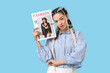 © Pixel-Shot - Beautiful young stylish happy woman with magazine on blue background