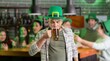 © Pixel-Shot - Handsome young man in green hat and with beer celebrating St. Patrick's Day in pub