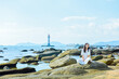 © sweetriver - One Chinese woman enjoying the beautiful landscape of beach and ocean and lighthouse at Sanya Dongtian Park (Daxiao Dongtian Scenic Area) in Sanya, Hainan, China