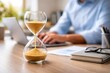 © Andrii  - Hourglass on Office Desk Symbolizing Time Management and Productivity