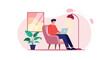 © MD - Man sitting in a comfortable armchair working on a laptop computer in a cozy room with a plant and floor lamp for remote work concepts.