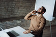 © Novak - Smiling professional man having a pleasant phone conversation and using a computer at his desk