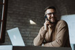 © Novak - Successful entrepreneur sitting at his desk, having a phone conversation and using a laptop, representing a relaxed yet productive corporate culture