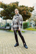 © DSMT - Woman stands in park wearing a unique knitted garment with fringe while trees and benches are in the background on an overcast day