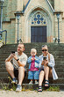 © DSMT - Family sits on steps outside church while using cell phones during afternoon
