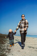 © DSMT - Mother and child walk hand in hand along beach under clear blue sky during daytime