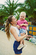 © DSMT - Mother holds son in garden with palm trees and flowers during daytime in warm weather