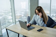 © DSMT - Woman working on laptop at a desk in modern office during winter with snow outside the window