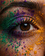 © Eva - Close-up of a brown eye covered with multicolored Holi powders