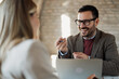© Novak - Businessman and businesswoman having a professional discussion while sitting at a table in a modern office