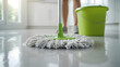 © Fathia A.M. - Person mopping clean floor with spin mop and green bucket, household cleaning