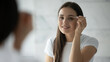 © fizkes - Making brows perfect. Head shot mirror portrait pretty young female use cosmetic tweezers to correct eyebrow shape in domestic bathroom enjoy delicate daily beauty ritual face care grooming procedure