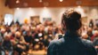 © Justlight - Medium shot of a speaker addressing a lively crowd in a community hall encouraging public involvement in social initiatives.