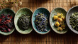 © CHAWAPON - Assorted tea leaves and flowers arranged in ceramic bowls on a bamboo mat