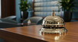 © PhotoArtHub - Shiny metallic bell on wood table, blurred teal background, suggestive of hotel reception, service, hospitality, and assistance