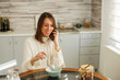 © Impact Photography - Business woman speaking on the phone while having breakfast at home