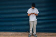 © carballo - a young, urban man in casual style looking at his phone on the street with a garage door in the background and space for copy