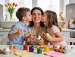 © Kate - A mother and her two children are painting Easter eggs together