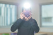 © fotolite - A Chinese student holds a camera with flash pointed directly at viewer, ideal for photography education, media studies, or creative arts concepts.